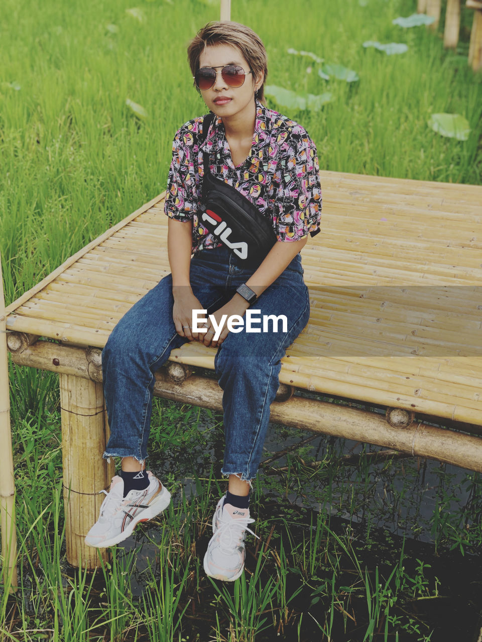 FULL LENGTH OF TEENAGE BOY SITTING ON BENCH IN GRASS