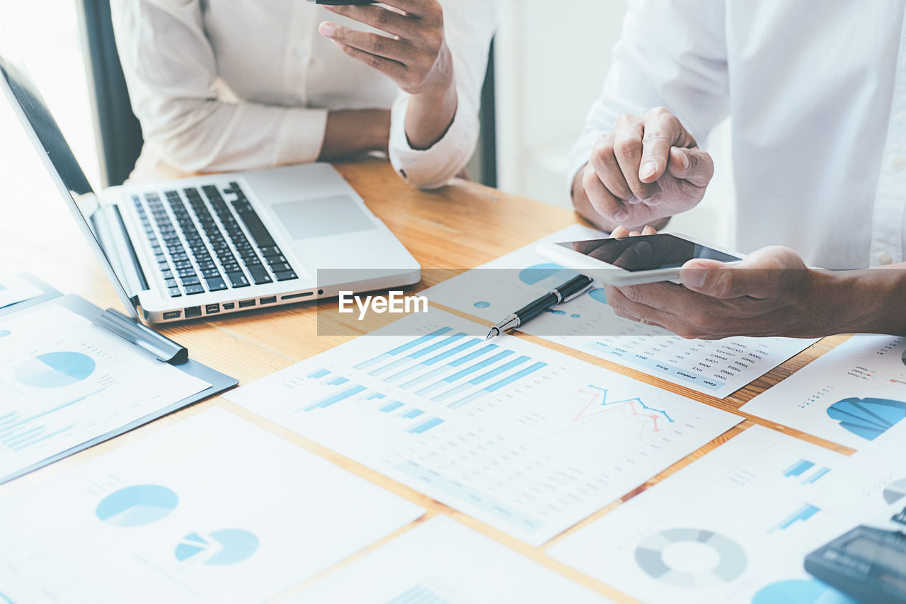 Midsection of business people working on table