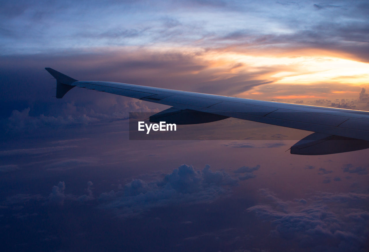 AIRPLANE WING OVER CLOUDS AGAINST SKY