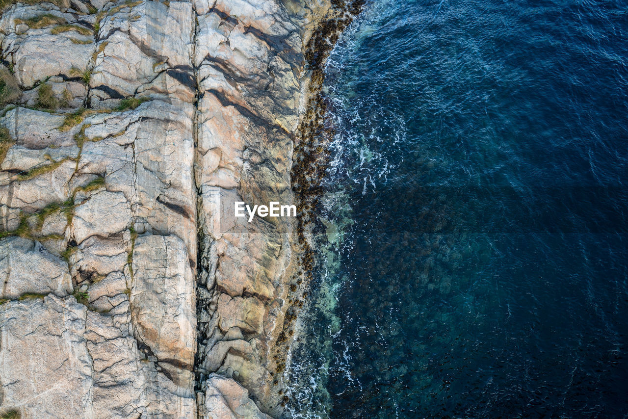 HIGH ANGLE VIEW OF ROCK FORMATION AT SEA