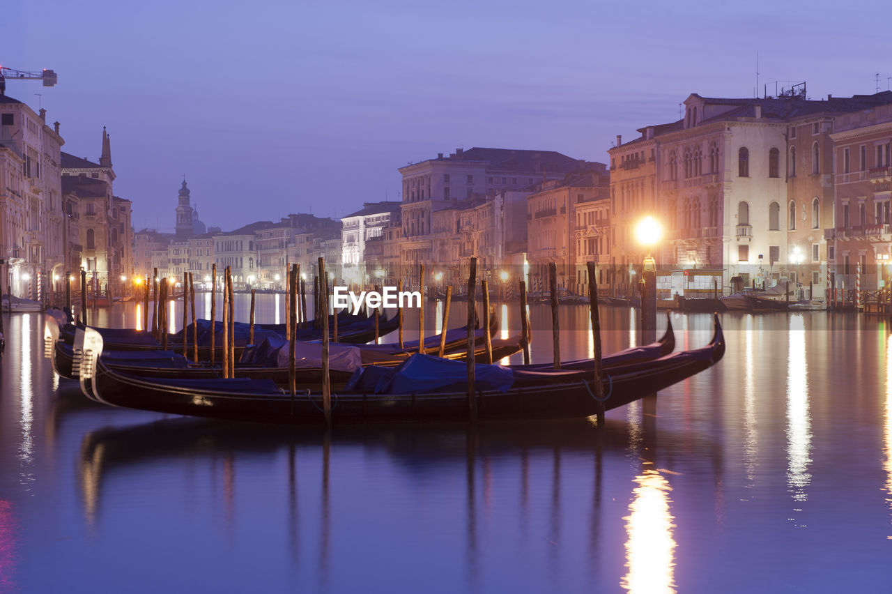 Gondolas moored on grand canal in city at night
