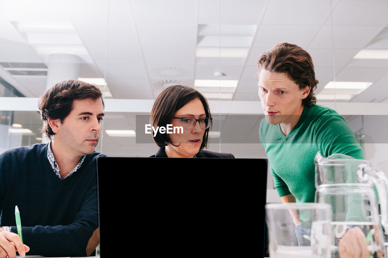 Business people discussing over laptop in office