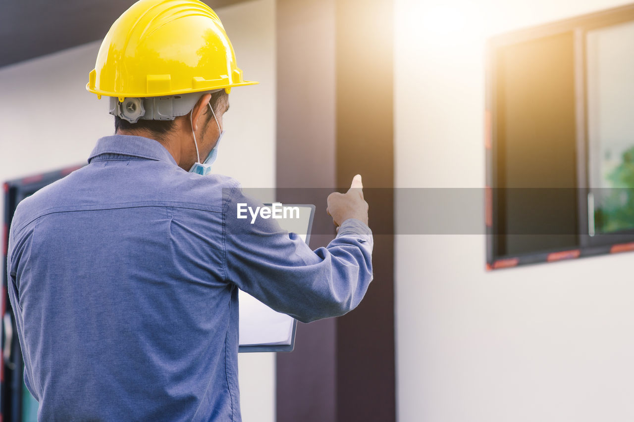 REAR VIEW OF MAN WORKING IN OFFICE