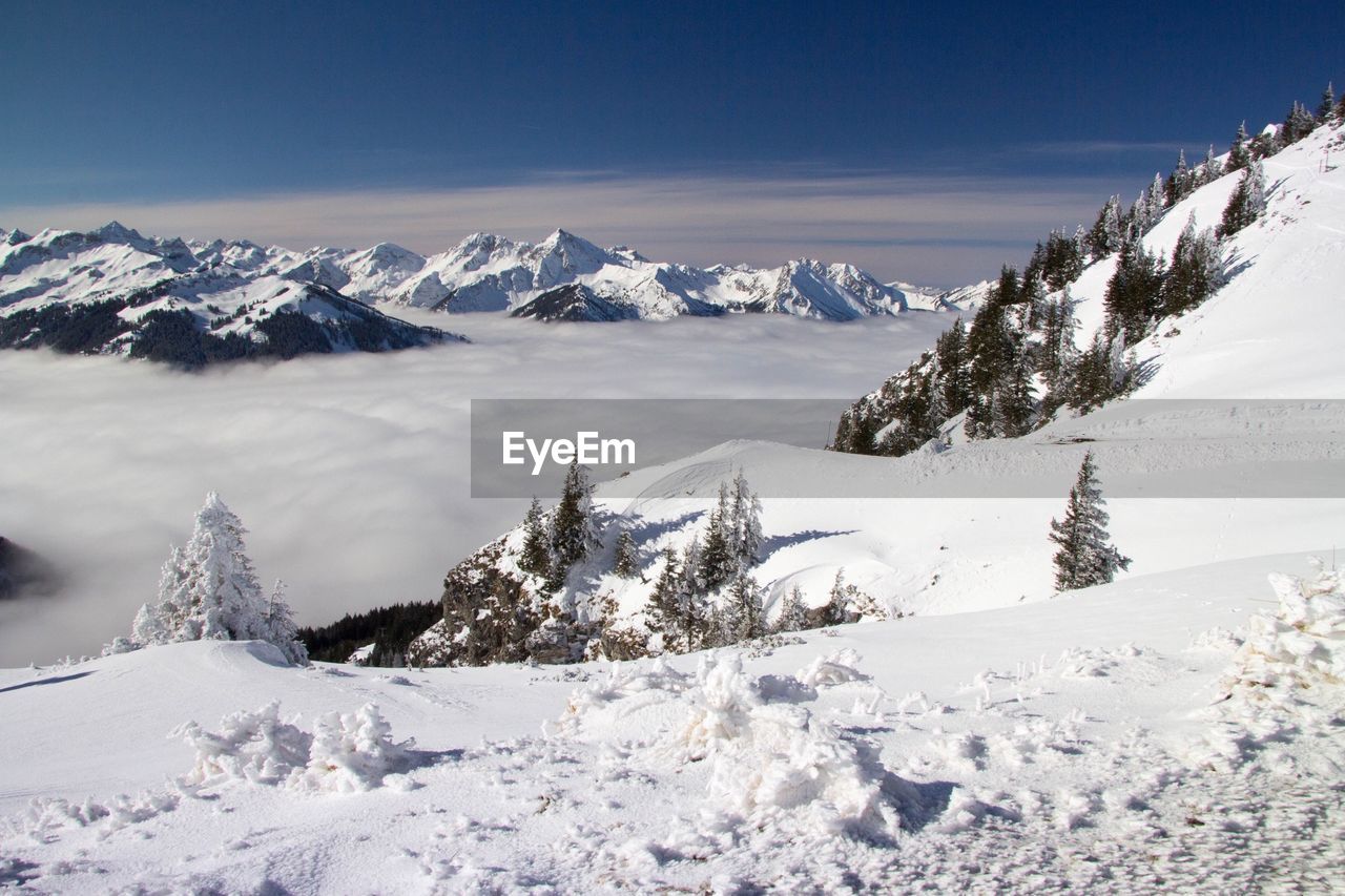 Scenic view of snow covered mountains against cloudy sky