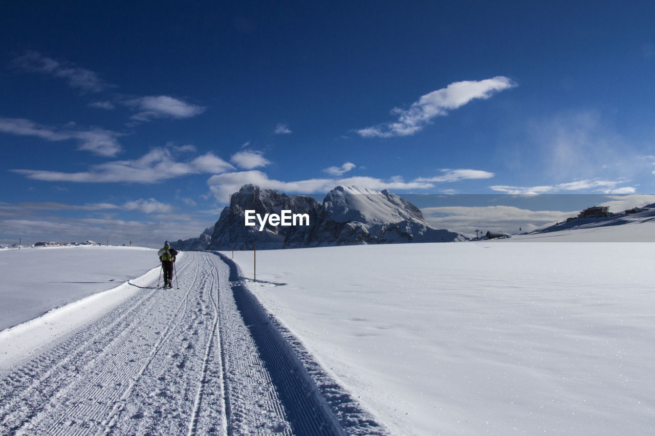 Woman walking on snowy land against snowcapped mountains