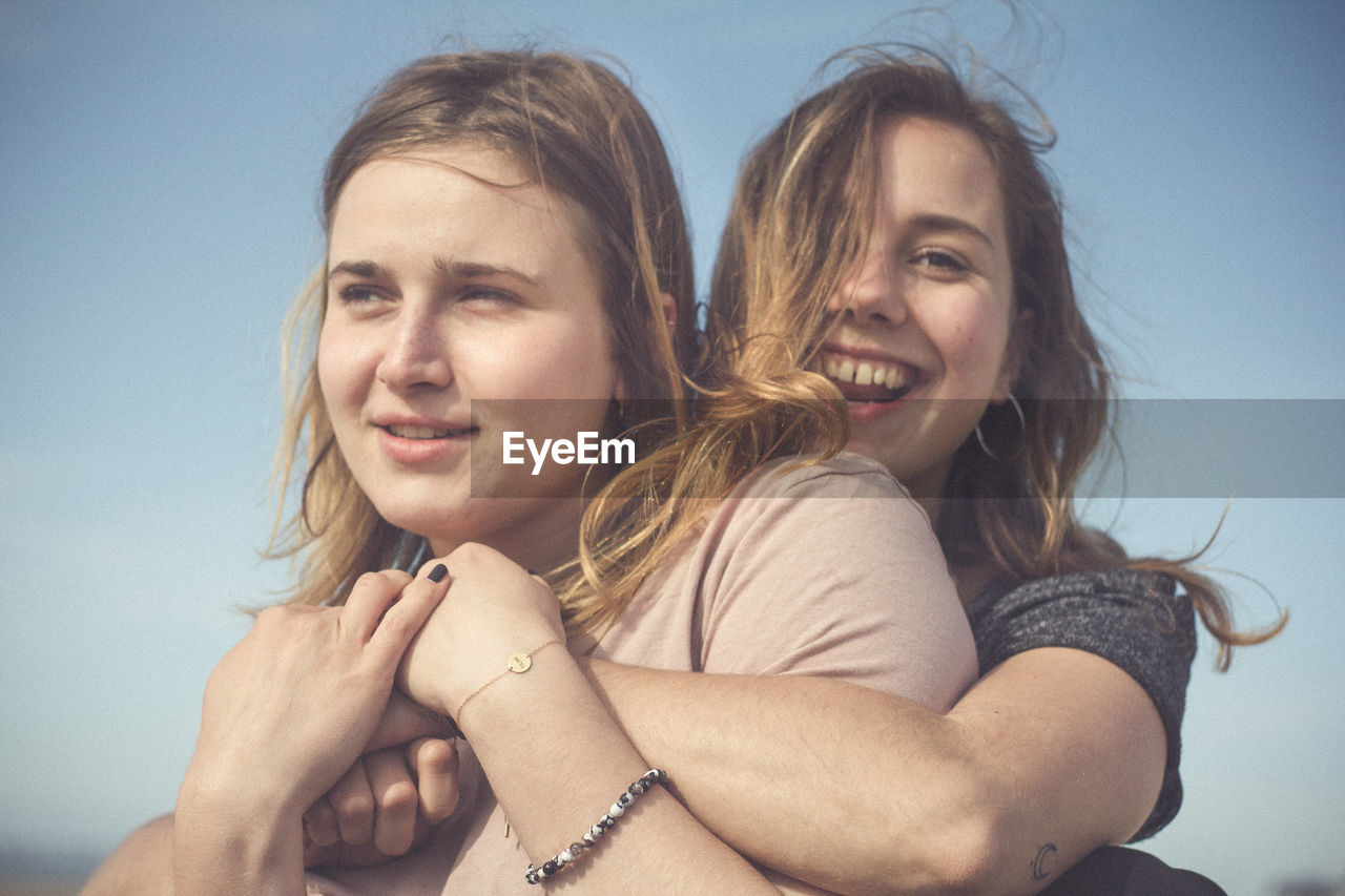 Close-up of cheerful siblings against sky