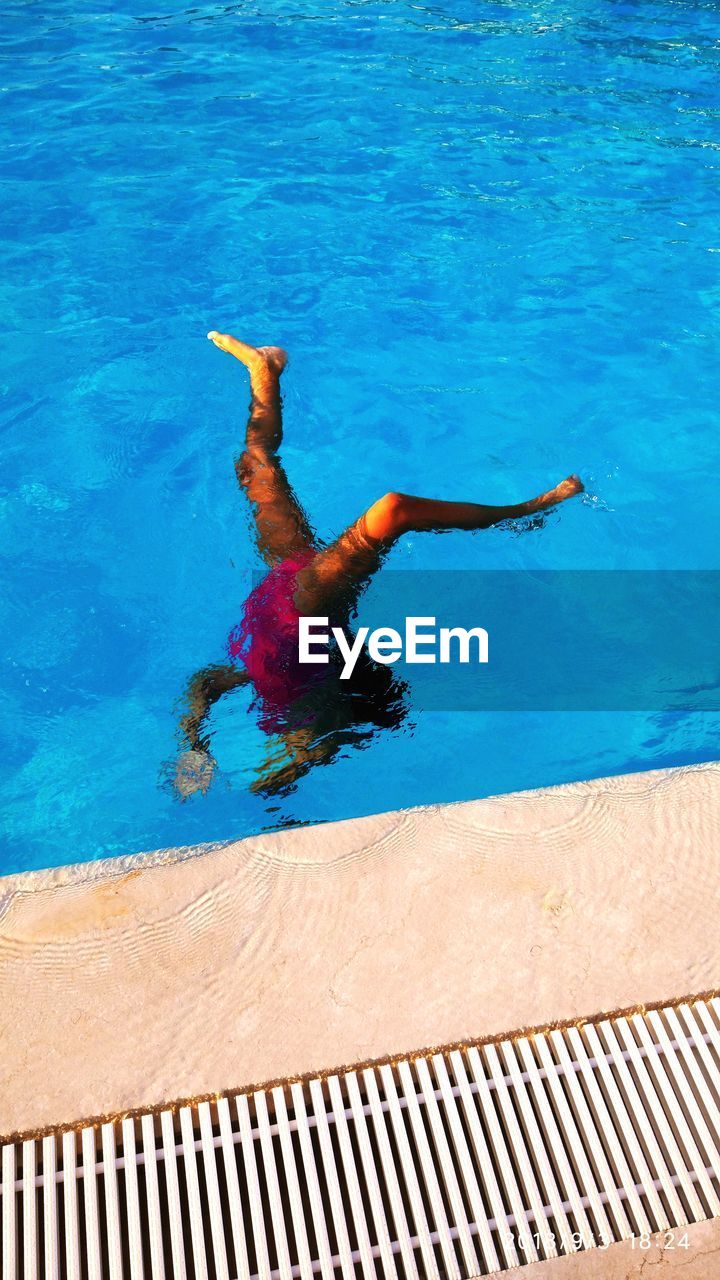 HIGH ANGLE VIEW OF MAN JUMPING SWIMMING IN POOL