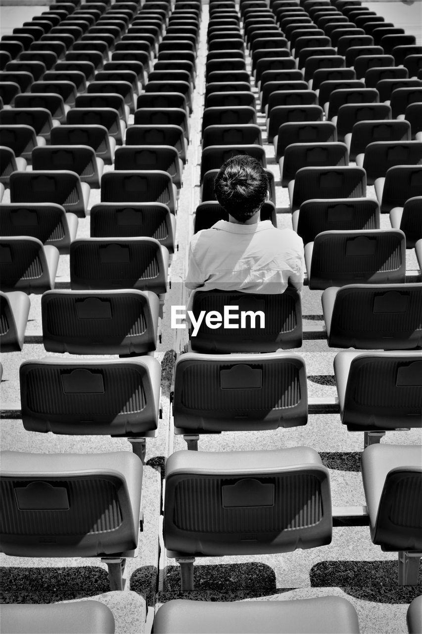 Rear view of boy sitting on chair at stadium