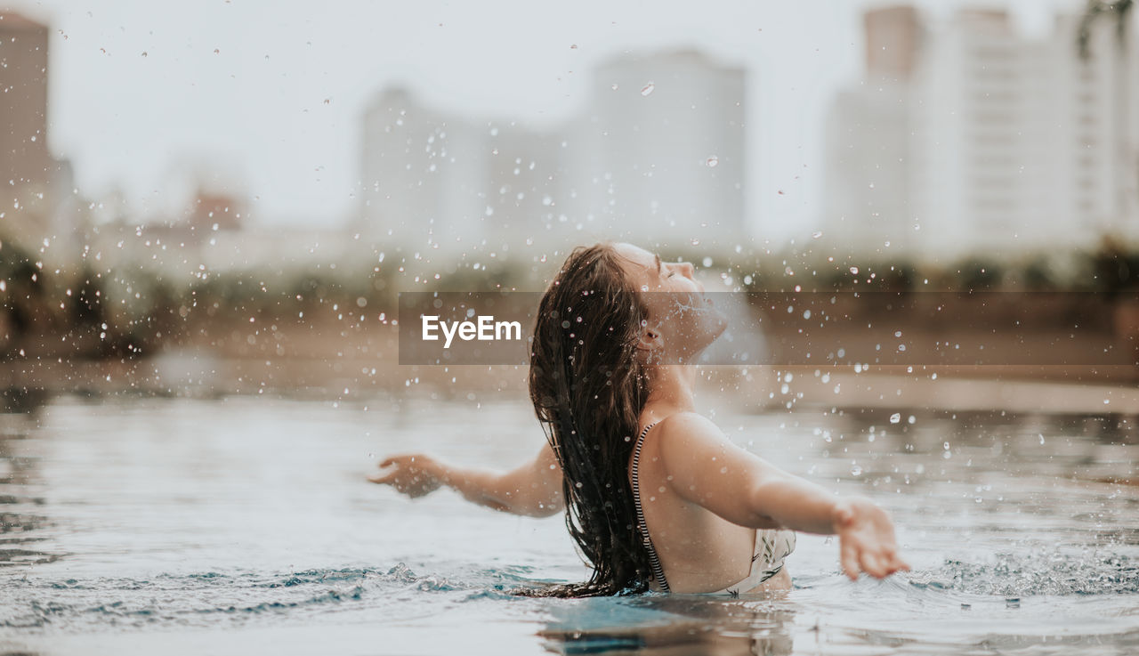 Side view of young woman with arms outstretched swimming in pool