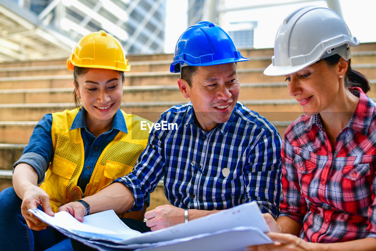 People working with blueprints while sitting on staircase