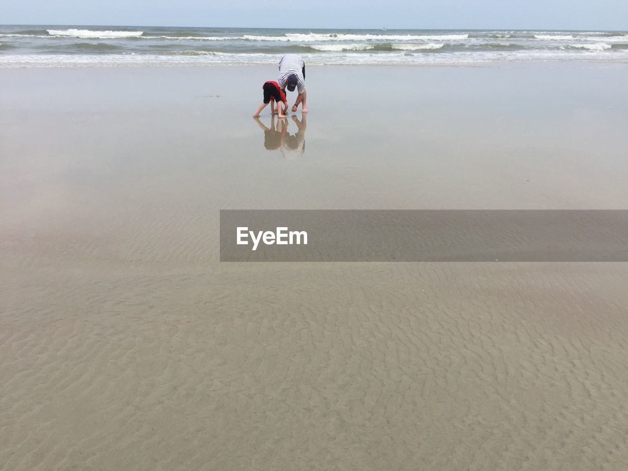 Father bending with son at sandy beach