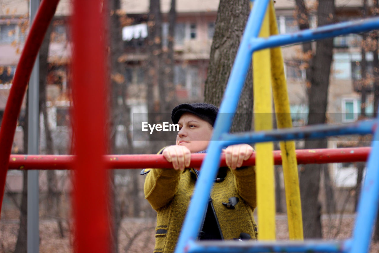 Woman standing on outdoors play equipment at playground during winter