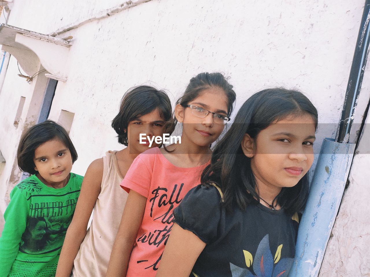 Portrait of siblings standing against wall