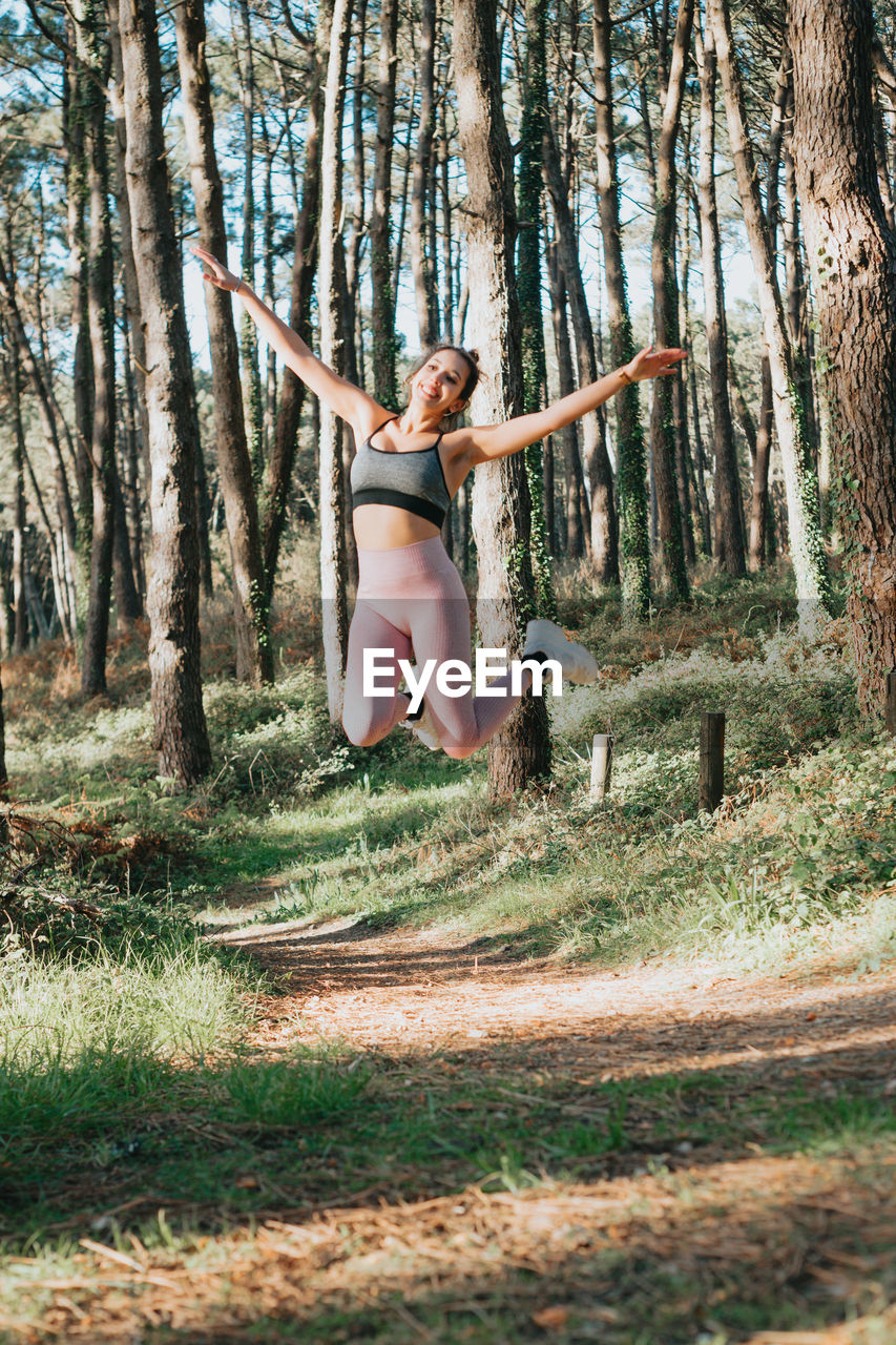 rear view of woman jumping in forest