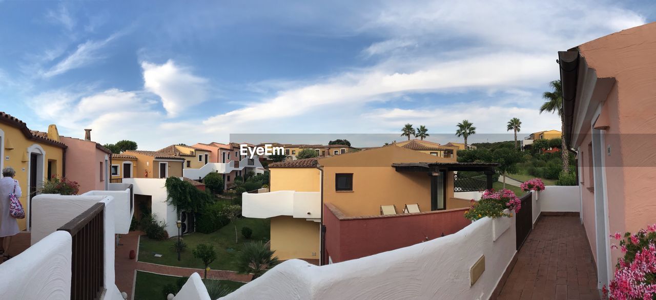 HOUSES BY BUILDINGS AGAINST SKY