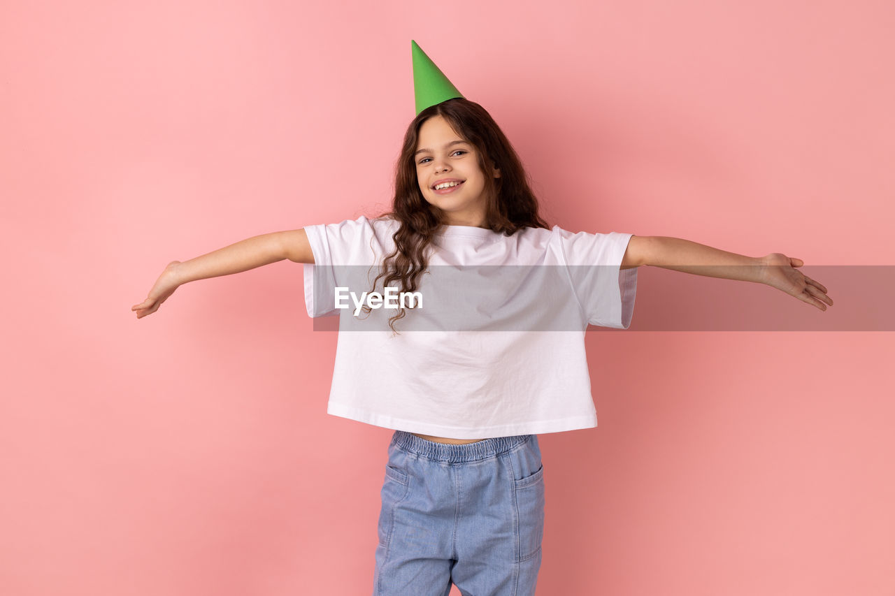 portrait of young woman standing against yellow background