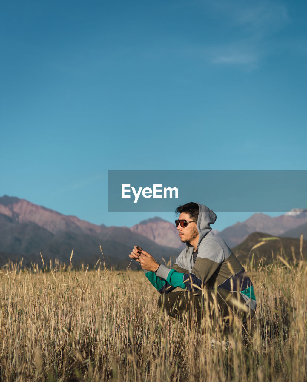 Young man sitting in a field next to the andes mountains