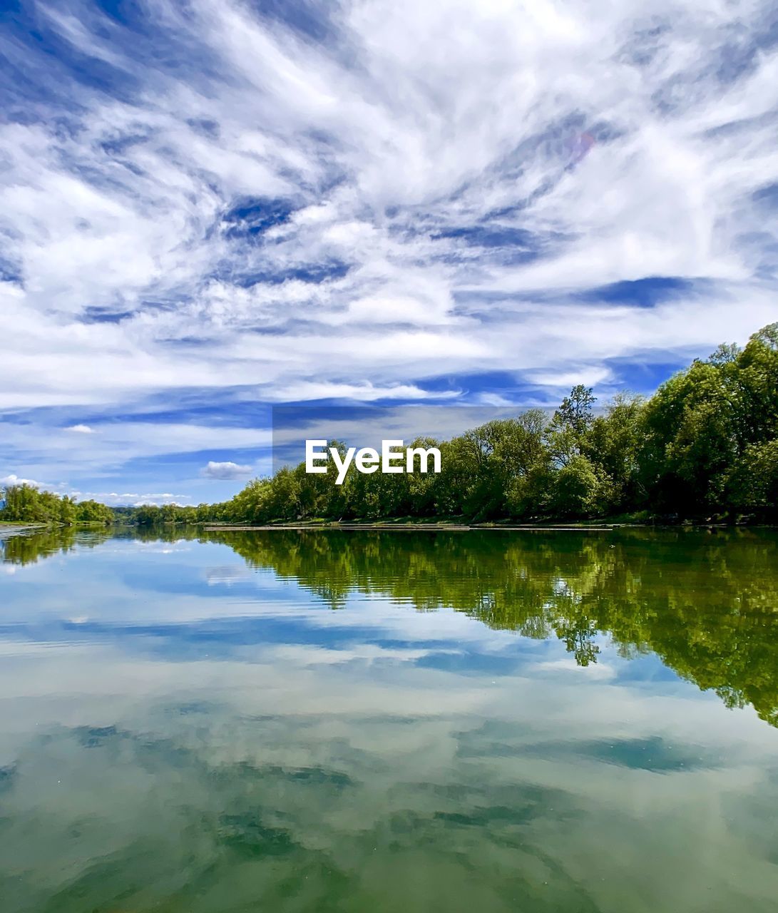 REFLECTION OF TREES IN LAKE AGAINST SKY