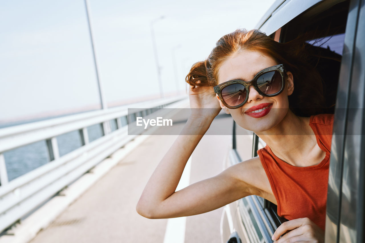 low angle view of young woman wearing sunglasses while standing by railing