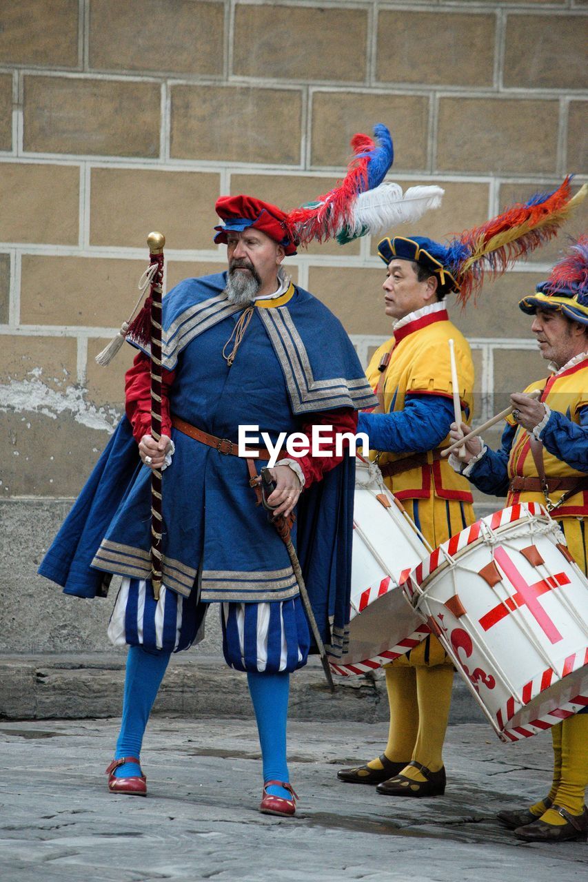 MEN WITH UMBRELLA STANDING AGAINST WALL