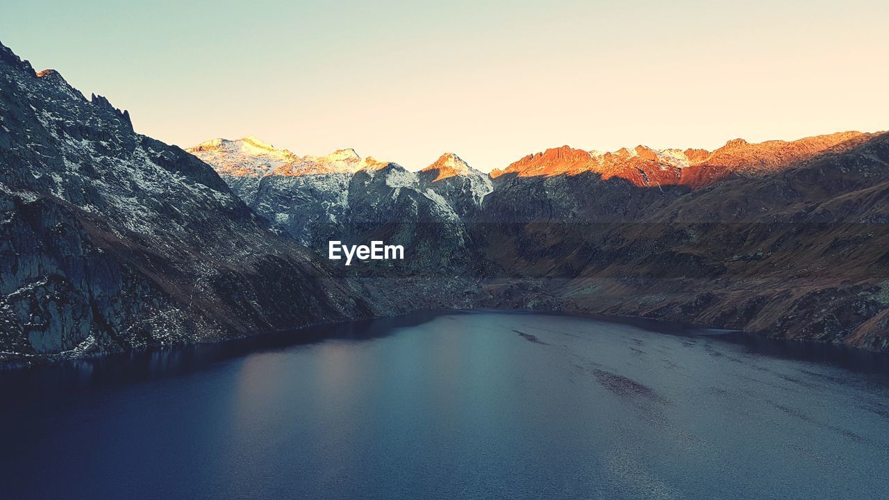 Scenic view of lake and mountains against clear sky