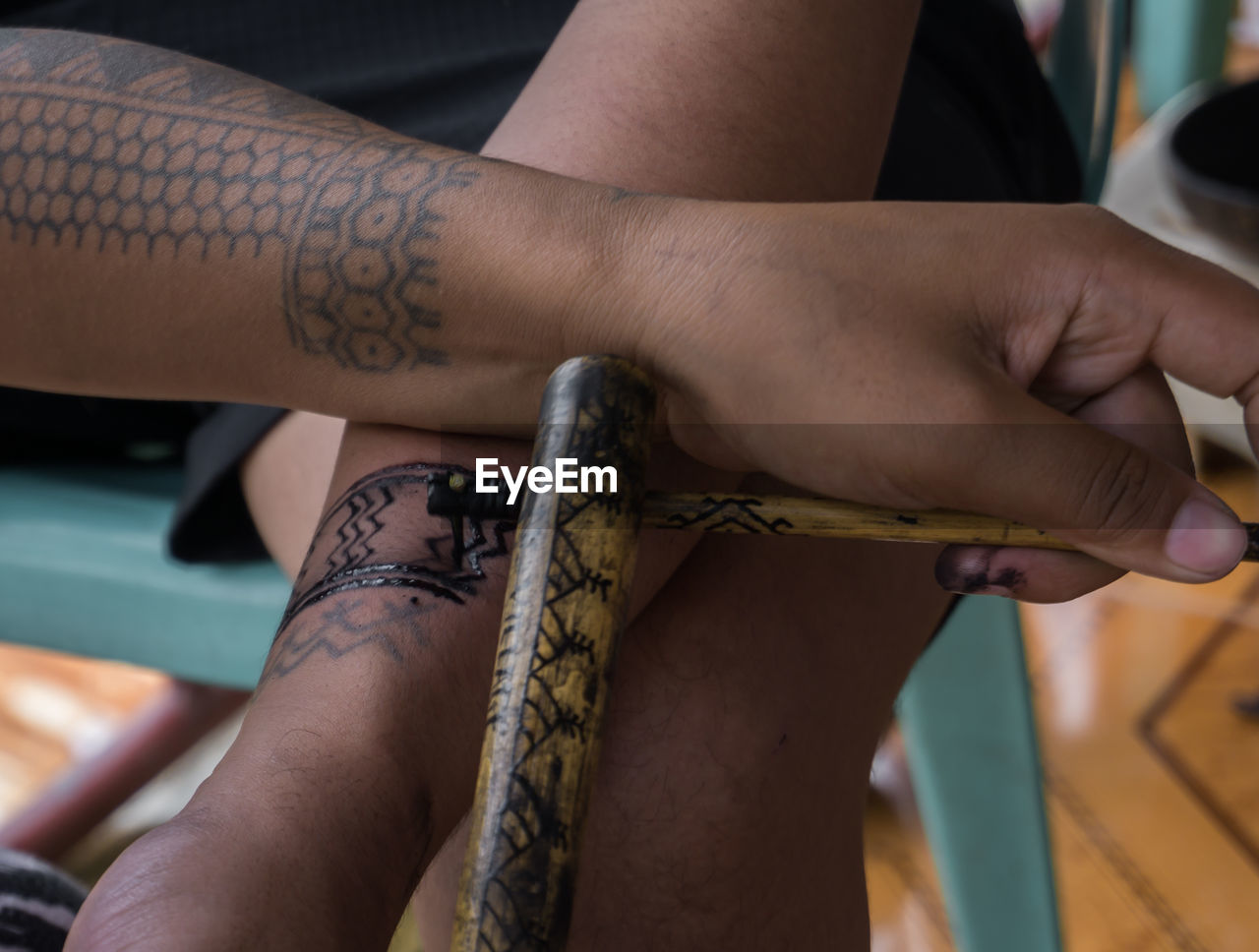 MIDSECTION OF MAN WITH TATTOO ON HAND