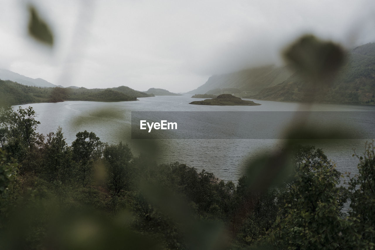 Scenic view of sea by mountains against sky