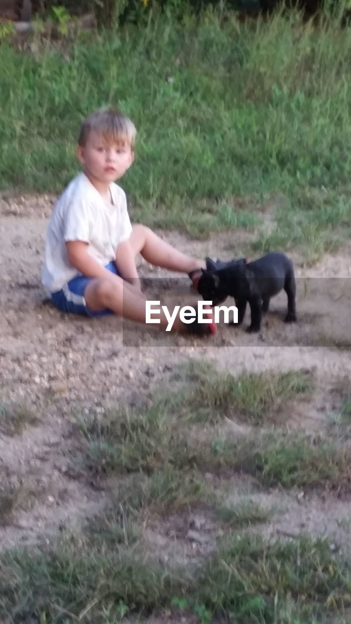 BOY PLAYING WITH DOG ON FIELD AT PARK