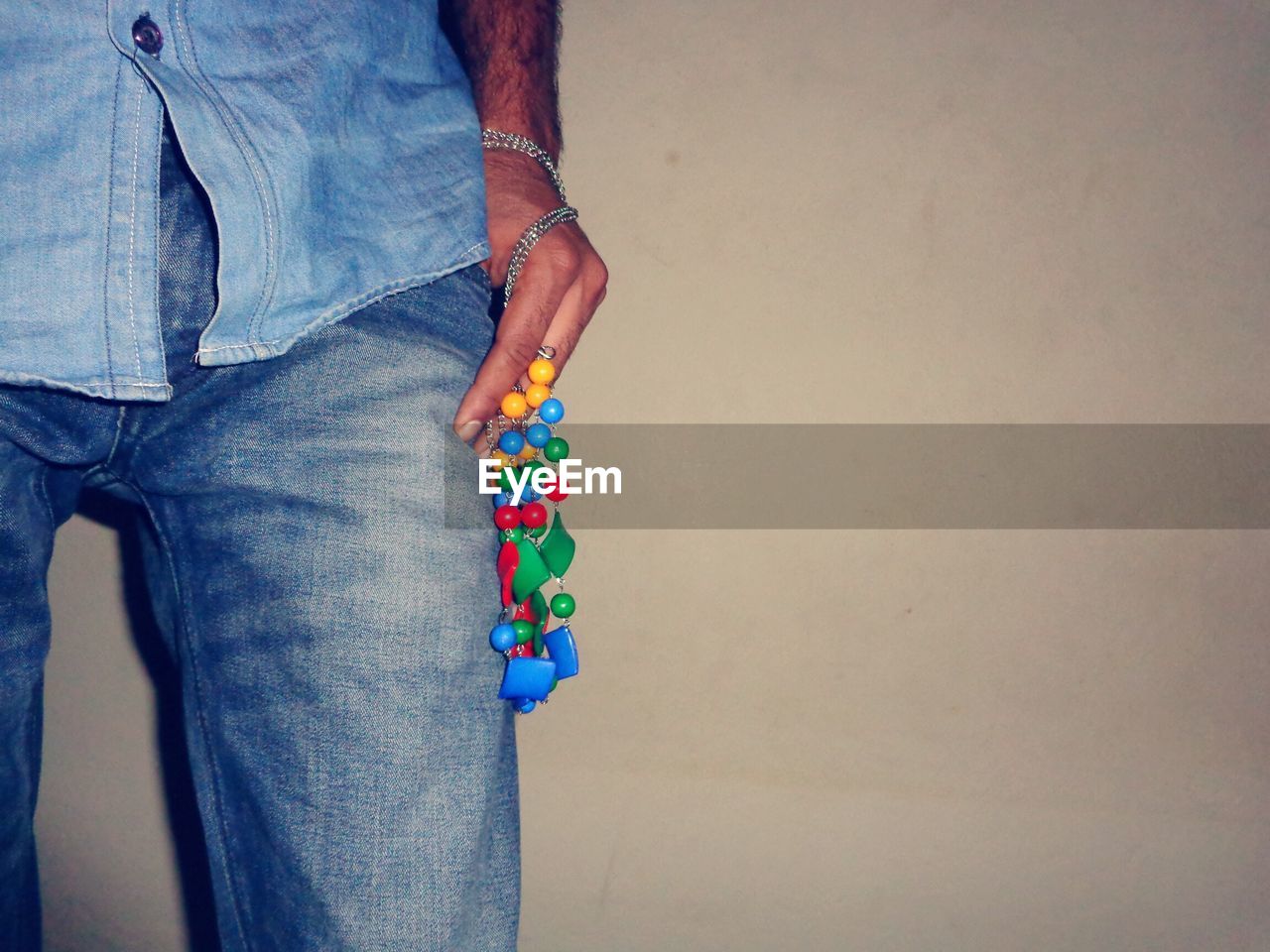 Midsection of man holding colorful decorations against wall