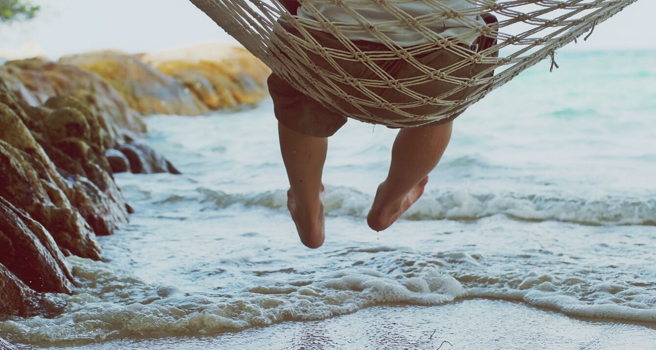 Low section of person on hammock at sea shore