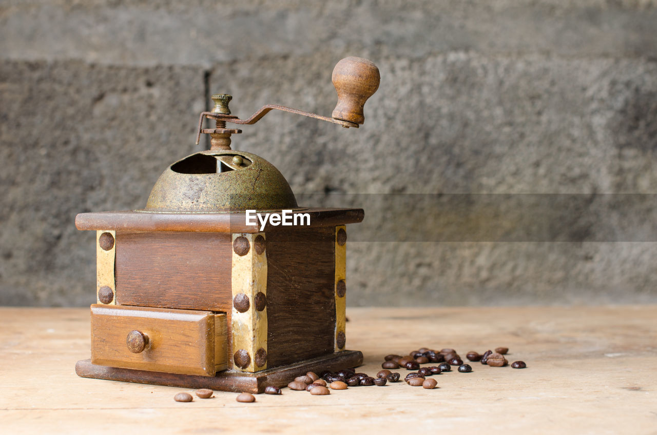 Close-up of coffee grinder on table against wall