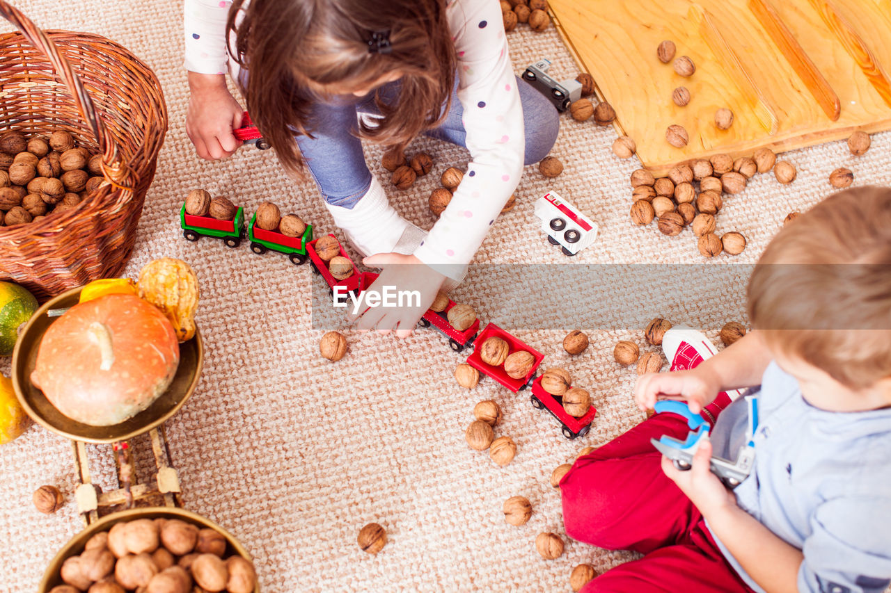 HIGH ANGLE VIEW OF GIRL AND WOMAN SITTING ON CUTTING BOARD