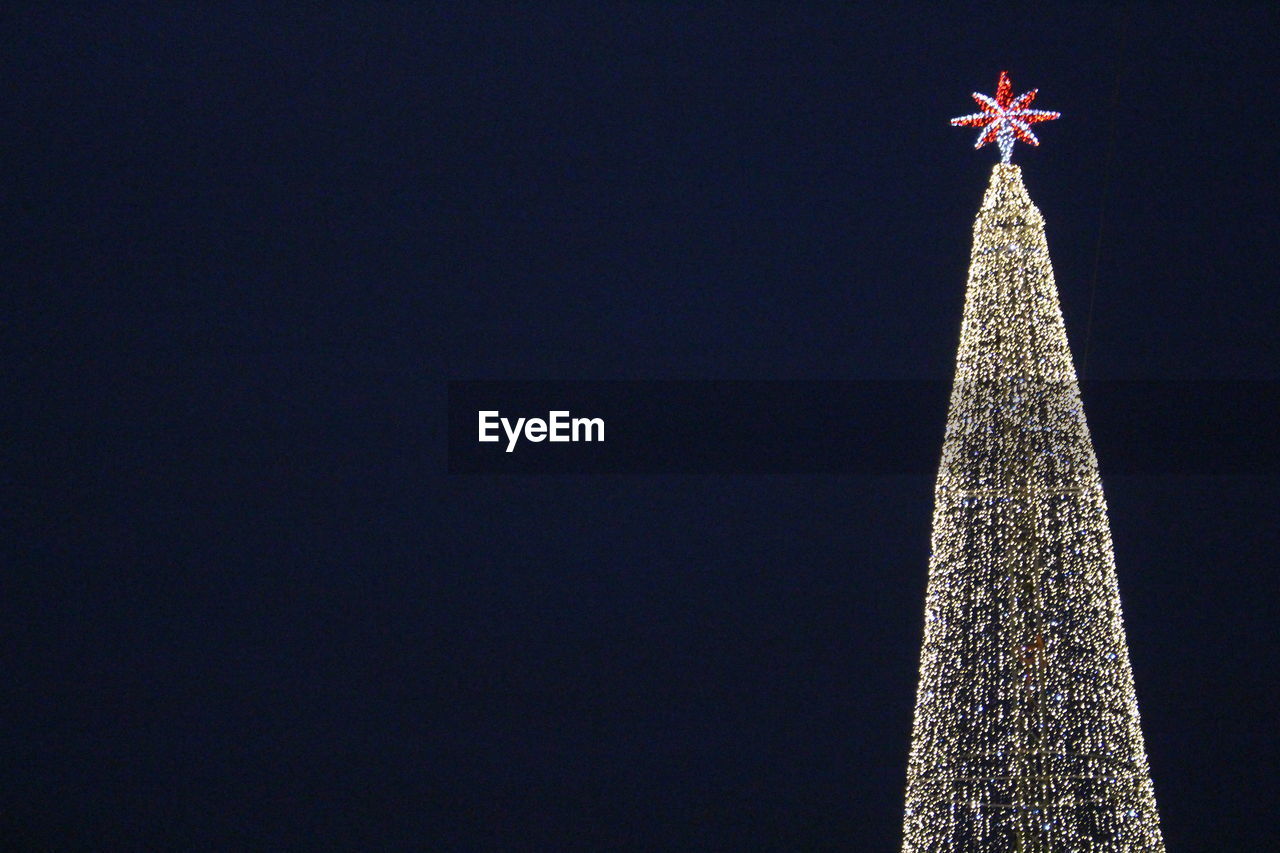 Low angle view of illuminated christmas tree against clear sky at night