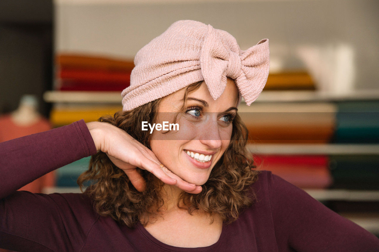 Joyful fashion designer playfully posing with a handmade pink bow headband