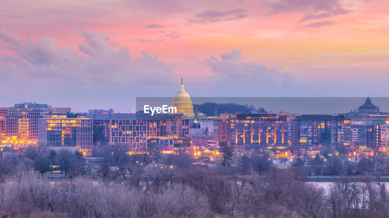 ILLUMINATED BUILDINGS IN CITY AGAINST SKY AT SUNSET