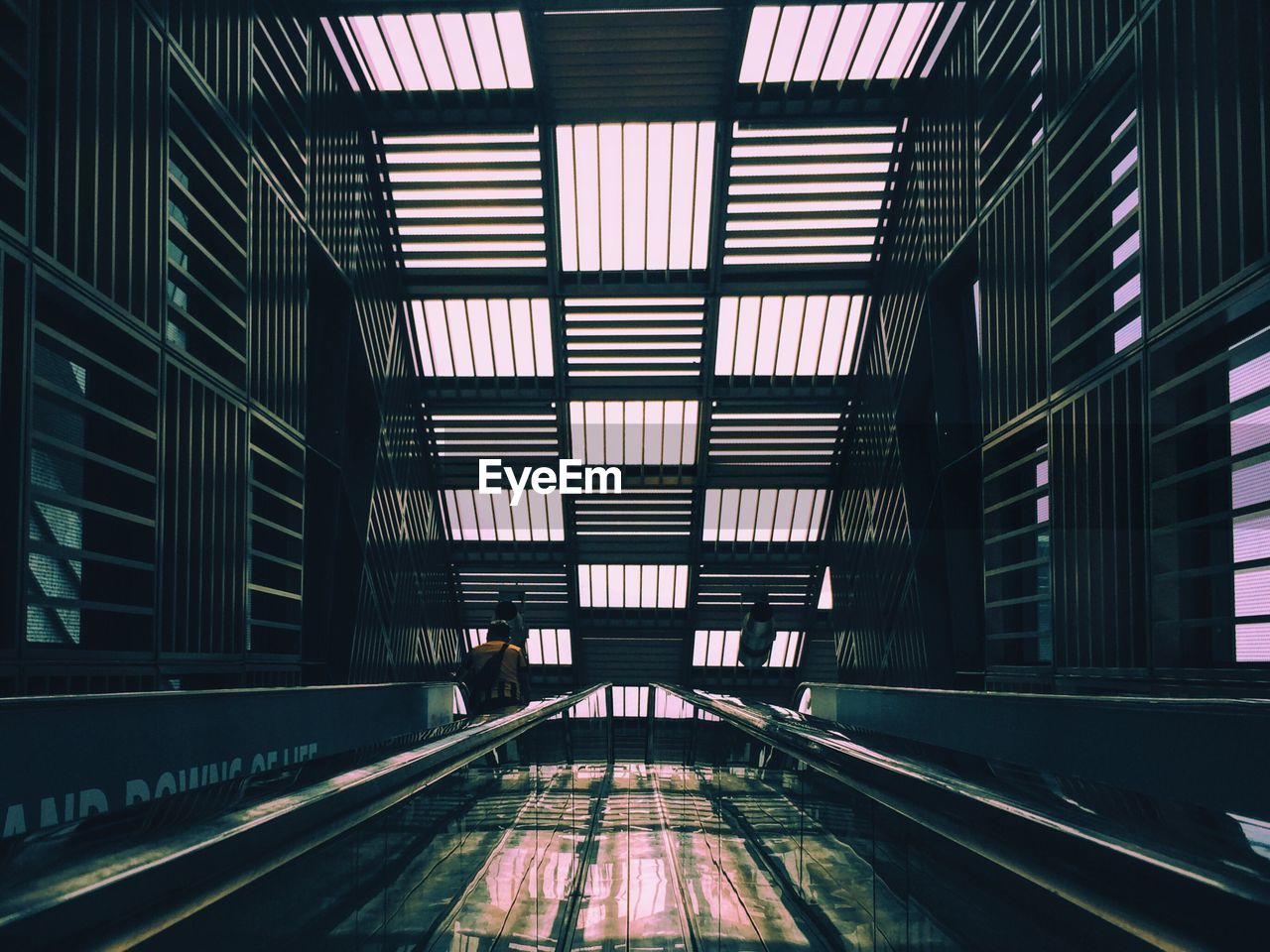 Low angle view of escalators against patterned ceiling in building