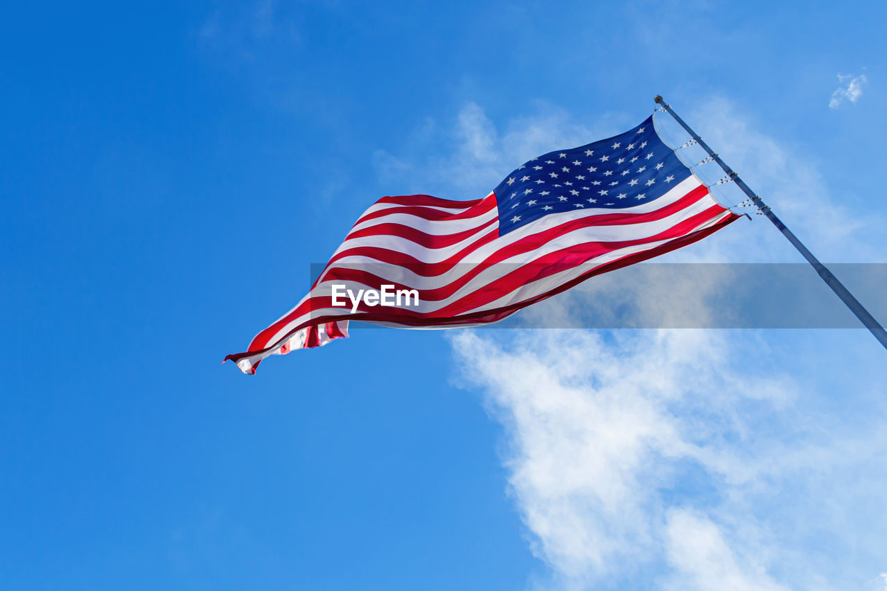 American flag blowing in the wind with a blue sky