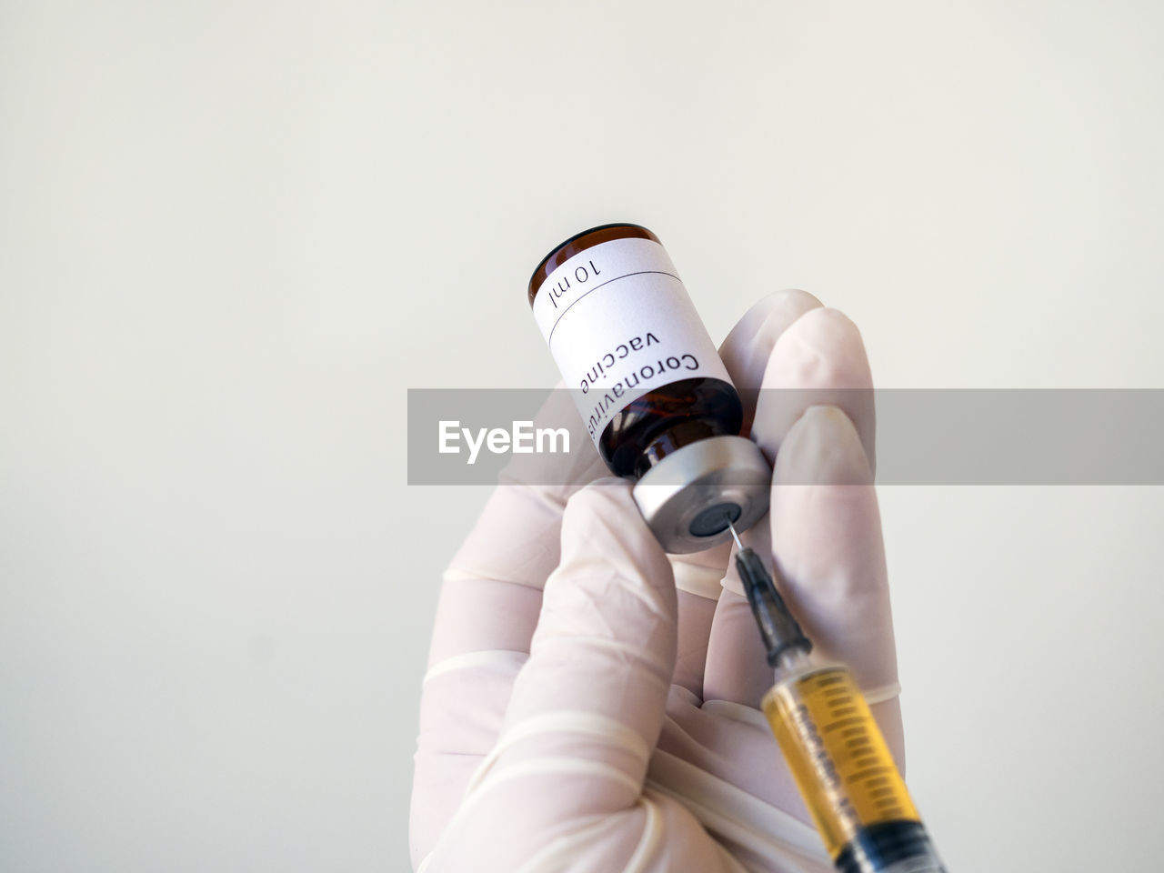 Doctor's hand holding a syringe of covid-19 vaccine and vaccine vial