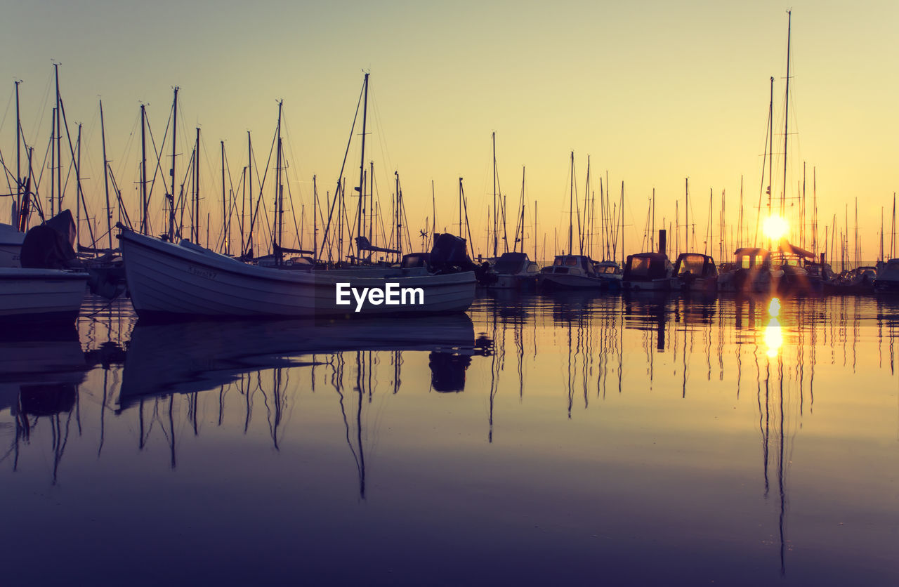 Sailboats moored at harbor