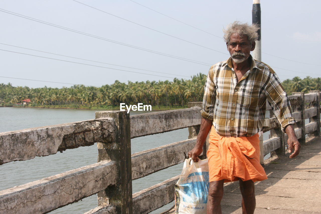 MAN STANDING ON SHORE AGAINST SKY