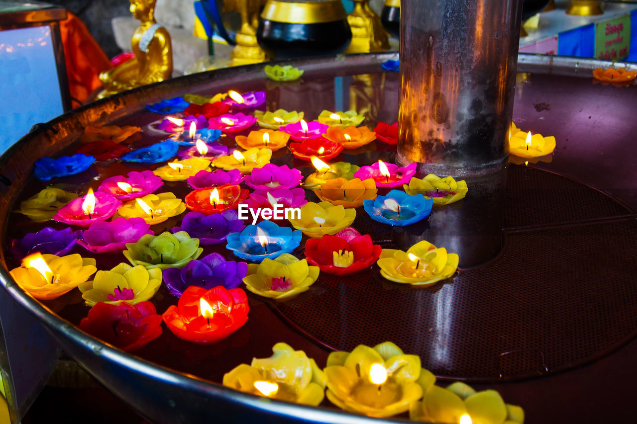 High angle view of colorful floral tea lights in bowl at temple