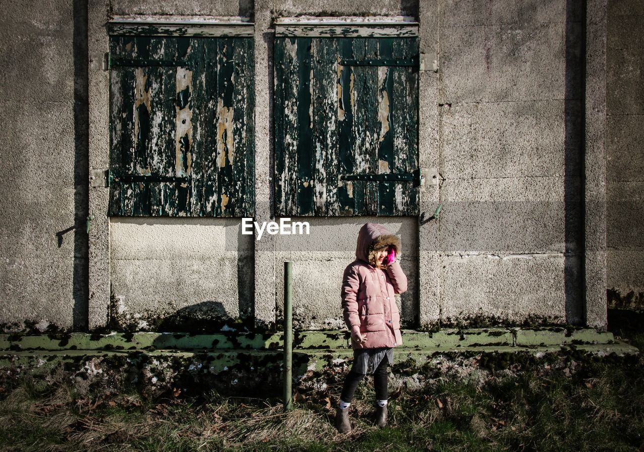 Girl standing by wall