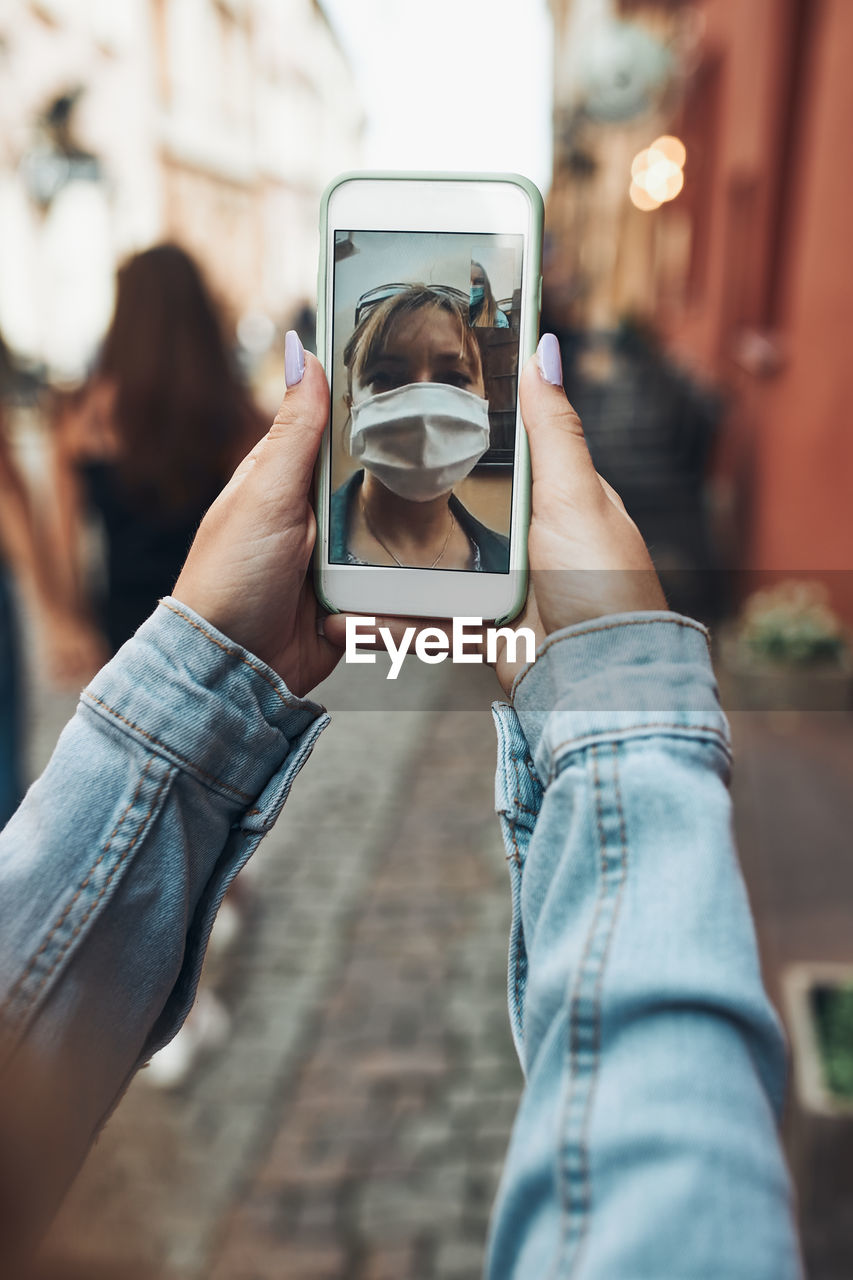 Young woman having video call talking while walking downtown chatting with friend wearing a mask