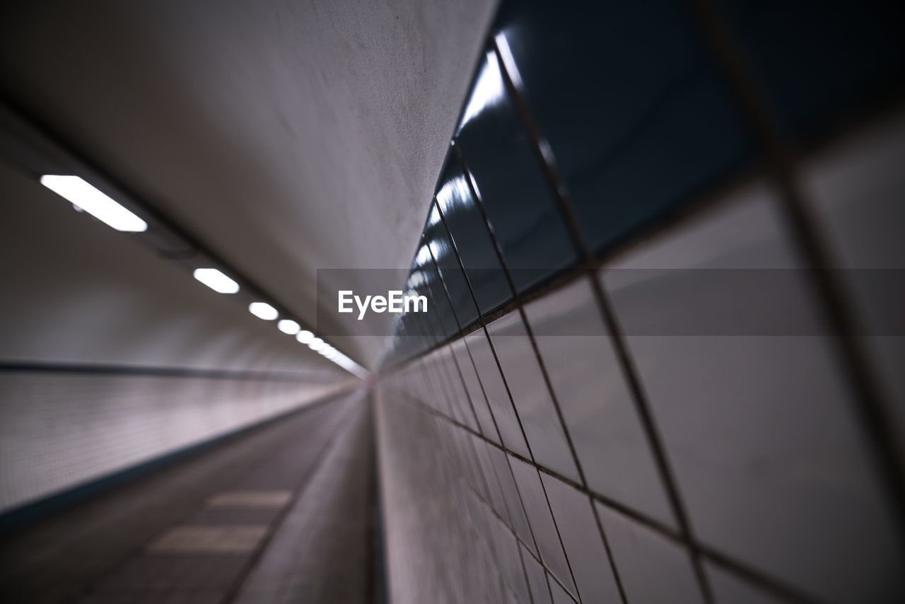 Close-up of tiled wall in illuminated tunnel