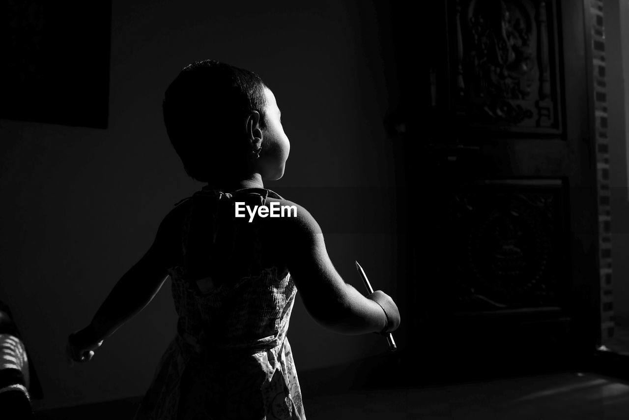 Rear view of girl standing in darkroom