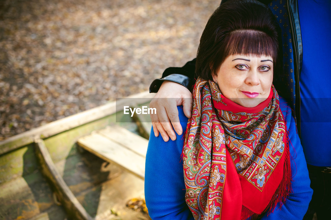 Portrait of mature couple sitting in forest during autumn