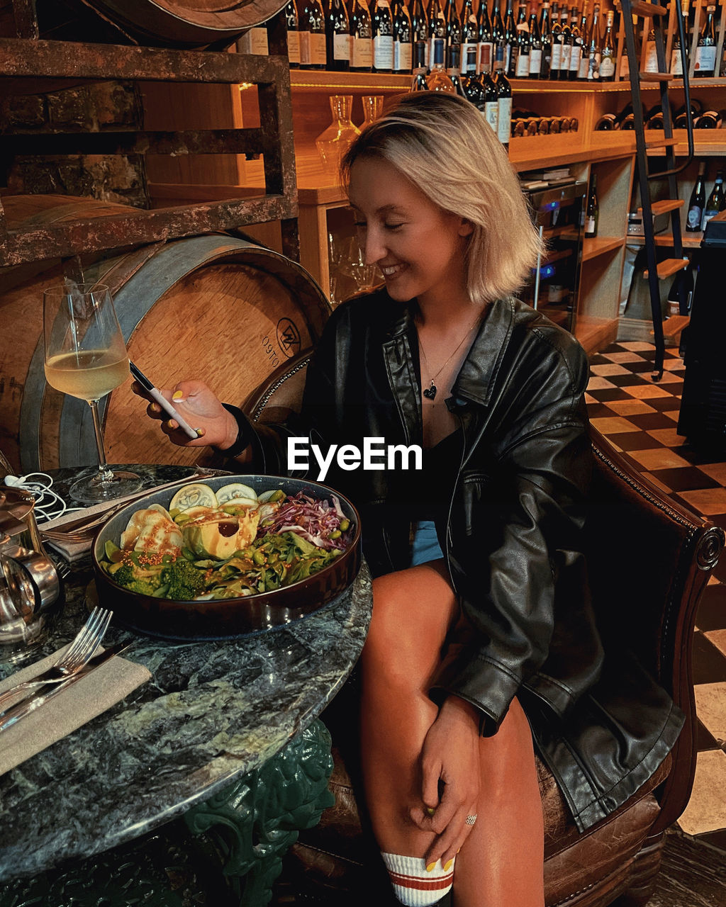 Young woman smiling and looking away while sitting on display in restaurant with wine