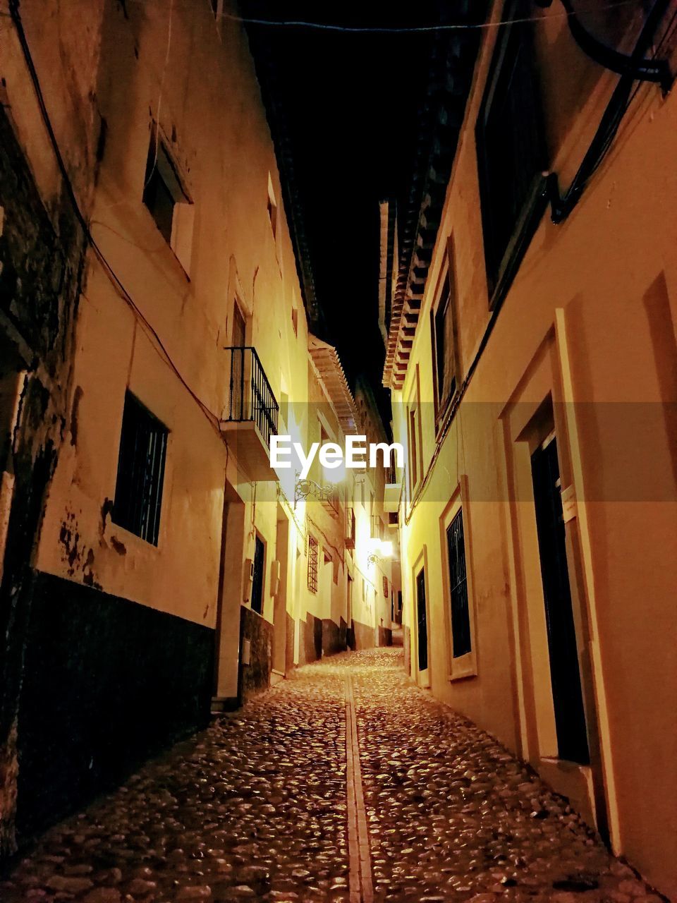 EMPTY NARROW ALLEY ALONG BUILDINGS