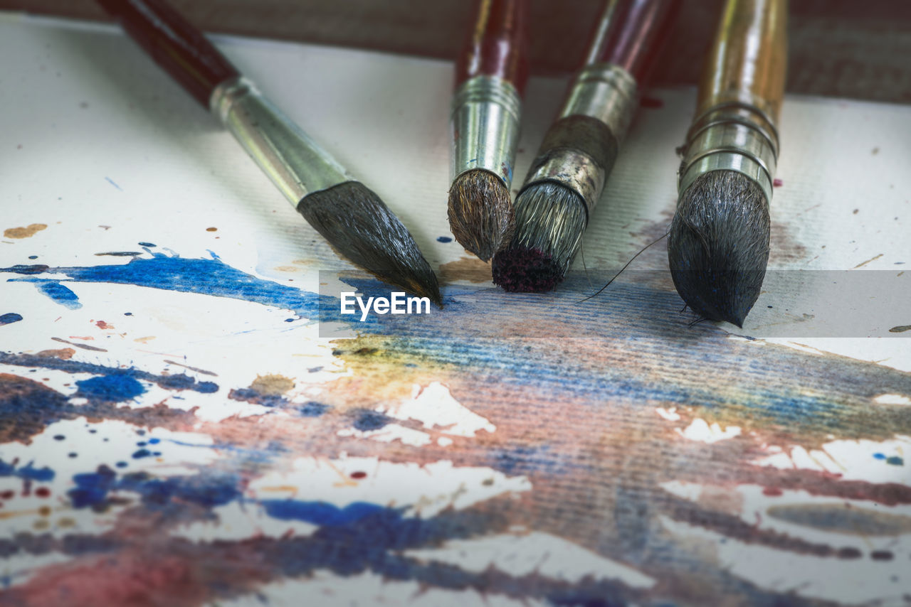 HIGH ANGLE VIEW OF PAINTBRUSHES ON FLOOR