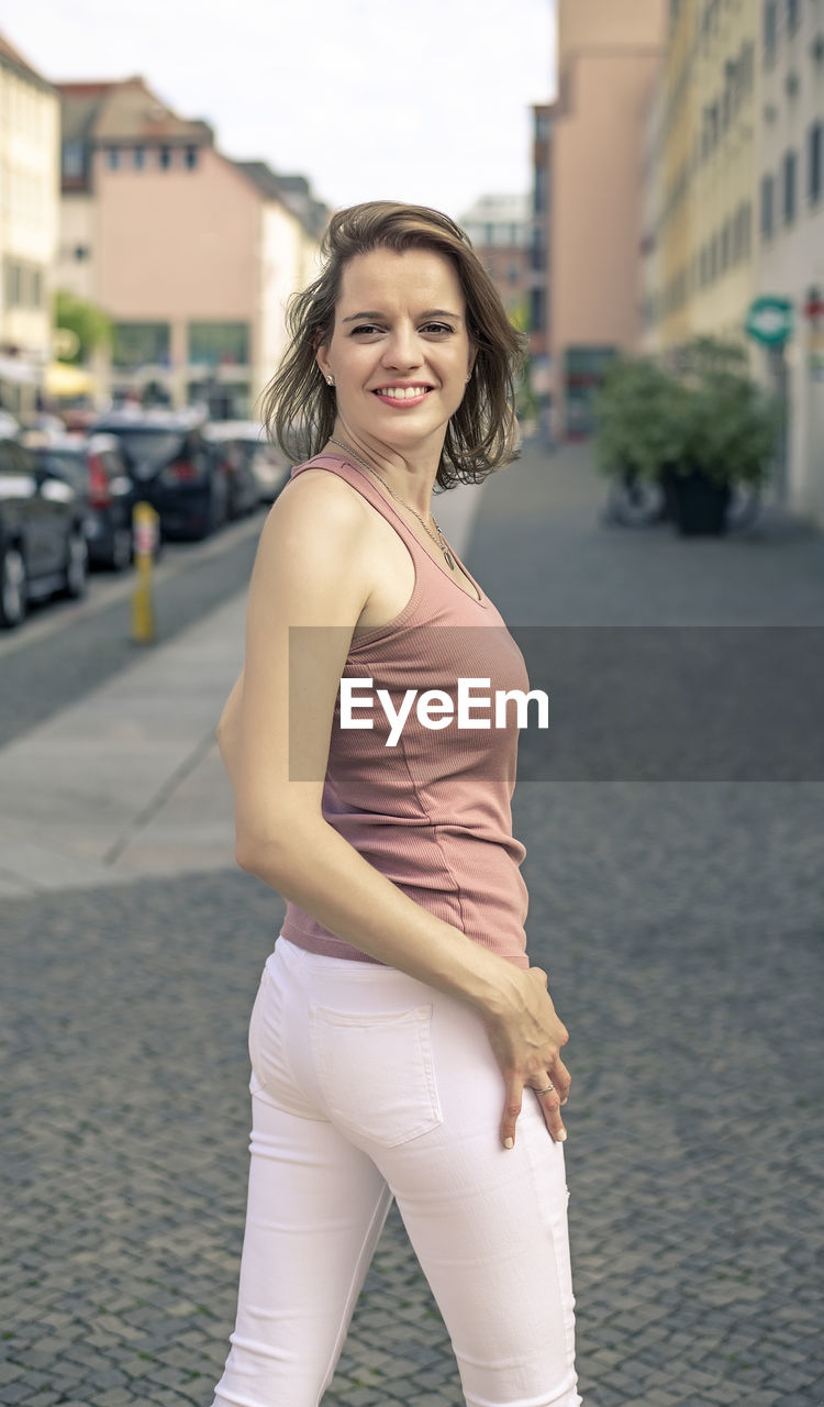 portrait of young woman standing on footpath